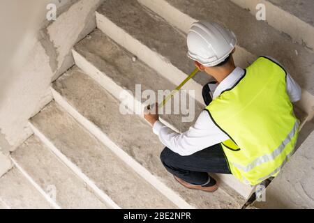 Inspecteur contrôle de la largeur d'escalier pour rénovation, ingénieur arpenteur en recherche sur le chantier. Concept de conseil en inspection à domicile Banque D'Images