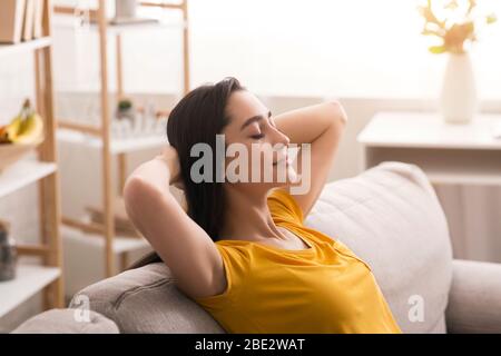 Restez calme et à la maison. Une jeune femme paisible se reposant sur un canapé dans le salon Banque D'Images