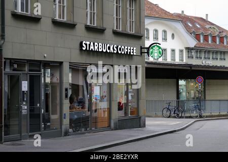 Allumé des signes de logo de Starbucks Coffee sur un mur d'un ancien bâtiment situé dans le centre-ville de Berne, Suisse, mars 2020. Le café Starbucks est une cafétéria. Banque D'Images