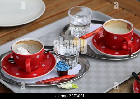 Table de cafétéria avec des tasses à café sales et des poubelles colorées. Les gens ont eu une pause café dans la cafétéria urbaine et ont laissé un gâchis derrière eux. Photo colorée. Banque D'Images