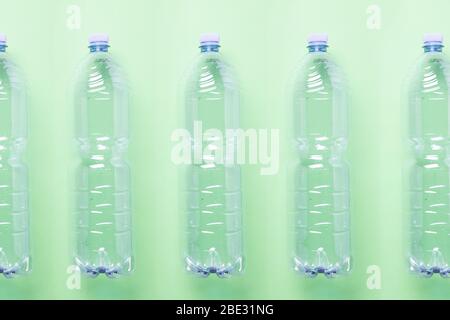 bouteilles en plastique vides minimalistes dans une ligne contre un fond vert clair pastel, plat, studio tourné Banque D'Images