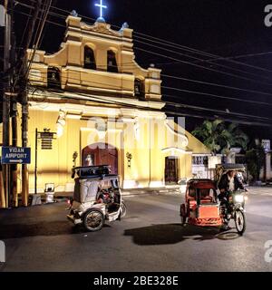 Tuk tuk tuk, moto ou tricyle équitation à Vigan à l'heure de la nuit devant une église Banque D'Images