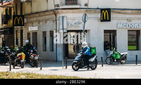 Cascais, Portugal - 11 avril 2020: Glovo et UberEats livrant des coursiers sur la moto devant un restaurant McDonalds pendant le Coronavirus Covid- Banque D'Images