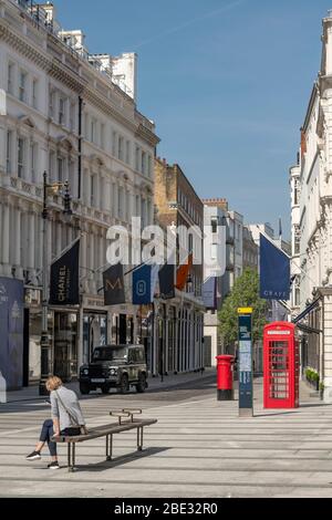 Une femme assise seule dans une rue commerçante vide et calme de Londres pendant la pandémie de virus Coronavirus 19 a fait son apparition. Les magasins sont fermés. Banque D'Images