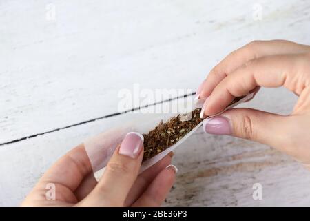 Mains de femme avec manucure enveloppant la joint de marijuana. Tordre l'articulation pour se détendre. Usage médical du cannabis. Banque D'Images