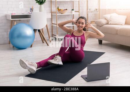 Restez en place, allez à l'extérieur. Faites de la place à une femme latine qui regarde des vidéos sportives en ligne et qui fait de l'exercice à la maison Banque D'Images