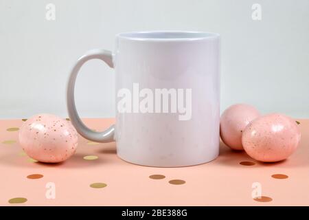 Cette maquette de tasse à café de Pâques est dotée d'un mug de 11 onces, sur fond de pois roses et or, entouré d'œufs de Pâques mouchetés au rose. Banque D'Images