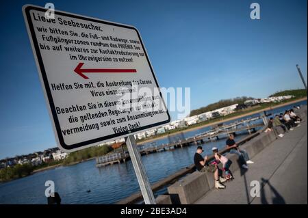 Dortmund, Allemagne. 11 avril 2020. Un panneau rappelle aux visiteurs du lac Phoenix d'utiliser le chemin circulaire dans le sens horaire seulement, afin de contenir la propagation du coronavirus en gardant une distance de sécurité avec d'autres personnes. Le lac artificiel sur le site d'une ancienne aciérie est l'une des destinations récréatives les plus fréquentées de la ville. Crédit: Bernd Thissen/dpa/Alay Live News Banque D'Images