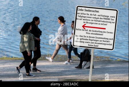 Dortmund, Allemagne. 11 avril 2020. Un panneau rappelle aux visiteurs du lac Phoenix d'utiliser le chemin circulaire dans le sens horaire seulement, afin de contenir la propagation du coronavirus en gardant une distance de sécurité avec d'autres personnes. Le lac artificiel sur le site d'une ancienne aciérie est l'une des destinations récréatives les plus fréquentées de la ville. Crédit: Bernd Thissen/dpa/Alay Live News Banque D'Images