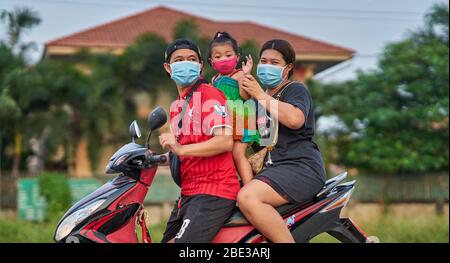 Une famille thaïlandaise voyageant sur une moto, tous portant des masques protecteurs, prise à Pathumthani, Thaïlande, en avril 2020. Banque D'Images