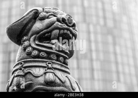 Gros plan d'une statue de lion chinois sur un rond point à Holloway Circus à Birmingham., soutenue par un nouveau gratte-ciel. Banque D'Images