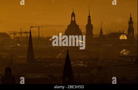 Dresde, Allemagne. 11 avril 2020. Le soleil se couche dans la soirée à l'horizon derrière le centre-ville avec Ernemannturm (l-r), Herz-Jesu-Kirche, l'Église de réconciliation, la Frauenkirche, l'Hausmannsturm, le Ständehaus, le dôme de l'Académie des Arts avec l'ange 'Fama' et la Hofkirche. Crédit: Robert Michael/dpa-Zentralbild/dpa/Alay Live News Banque D'Images