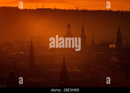 Dresde, Allemagne. 11 avril 2020. Le soleil se couche dans la soirée à l'horizon derrière le centre-ville avec Ernemannturm (l-r), Herz-Jesu-Kirche, l'Église de réconciliation, la Frauenkirche, l'Hausmannsturm, le Ständehaus, le dôme de l'Académie des Arts avec l'ange 'Fama' et la Hofkirche. Crédit: Robert Michael/dpa-Zentralbild/dpa/Alay Live News Banque D'Images