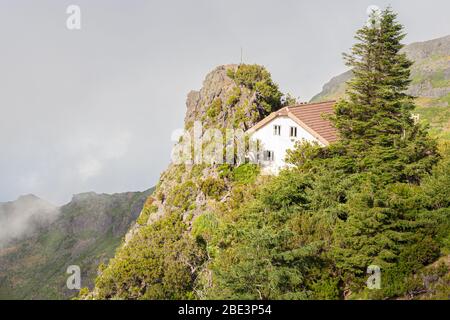 Une maison blanche avec un toit carrelé dans les montagnes parmi les nuages. Banque D'Images