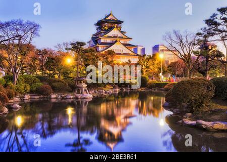Jardin japonais traditionnel avec étang et lumières vives au lever du soleil dans le parc historique de la ville d'Osaka. Banque D'Images