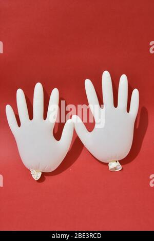 Gants médicaux blanc isolé sur fond rouge. Protection Banque D'Images