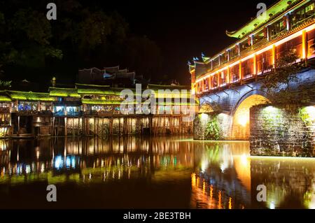 Le pont de hongqiao, un site touristique, s'est éclairé la nuit sur la rivière du tuojiang dans le village de Fenghuang, dans la province chinoise de hunan. Banque D'Images