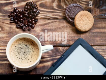 bouchon de café avec mousse, ebook, gâteaux, grains de café en forme de coeur sur la table en bois. Plat avec pas de personnes Banque D'Images