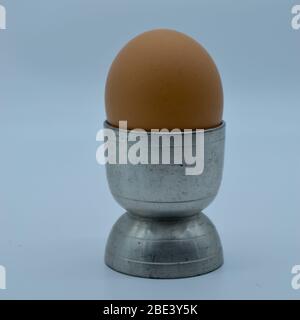 Gobelet rétro en argent ou en étain avec œuf bouilli dans un cliché de studio isolé Banque D'Images