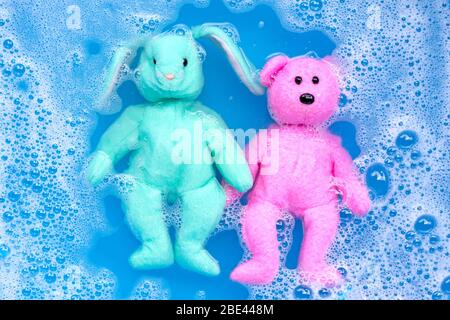 Poupée lapin tremper avec toy ours en dissolution de l'eau pour la lessive avant de les laver. Blanchisserie concept, vue d'en haut Banque D'Images