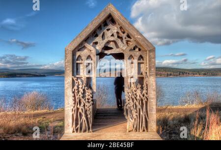 Cabane en bois avec sculptures près d'un lac à Kielder Water & Forest Park, Royaume-Uni Banque D'Images