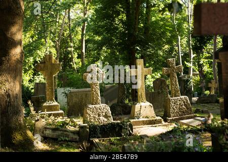 La lumière du soleil brille sur les croix de pierres tombales au cimetière Highgate, à Londres, un jour d'été. Banque D'Images