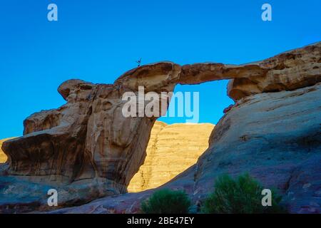 Jordan, Wadi Rum, une personne est debout sur le sommet de la formation Arch au coucher du soleil Banque D'Images