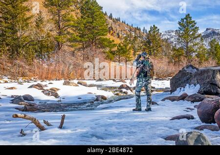 Hunter avec des vêtements de camouflage et fusil regardant avec des jumelles; Denver, Colorado, États-Unis d'Amérique Banque D'Images