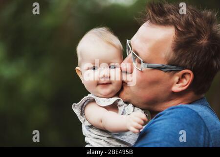 Un père tenant sa petite fille et la câliner et l'embrasser à l'extérieur pendant l'automne; Edmonton, Alberta, Canada Banque D'Images