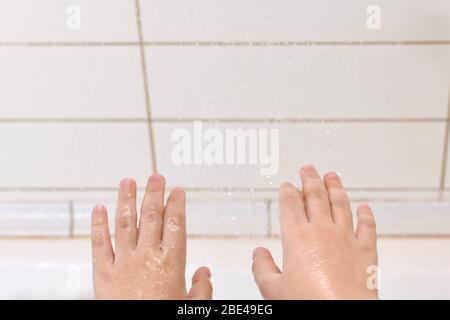 Un fragment d'enfants a étiré les mains à l'extérieur de la paume vers le haut sous les gouttelettes d'eau qui tombent. Banque D'Images