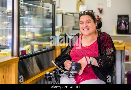 Femme maorie avec paralysie cérébrale en fauteuil roulant dans une cafétéria; Wellington, Nouvelle-Zélande Banque D'Images