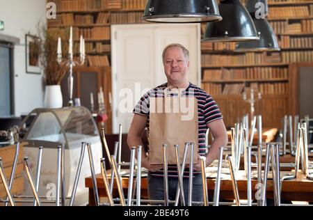 Potsdam, Allemagne. 7 avril 2020. Conrad, responsable de service, se tient au restaurant « Genusswerkstatt » du Filmmuseum, entre les chaises hautes et tient un sac en papier avec des boîtes à nourriture dans ses mains. Les clients ne sont pas autorisés à s'asseoir dans des restaurants lors des restrictions imposées par le Corona danger. (Pour les boissons fraîches et le risotto savoureux: Pour aller au signe de Corona) crédit: Soeren Stache/dpa-Zentralbild/ZB/dpa/Alay Live News Banque D'Images