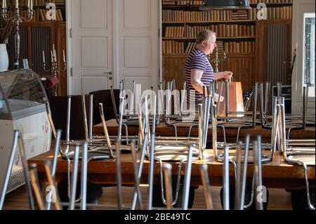 Potsdam, Allemagne. 7 avril 2020. Conrad, responsable de service, se tient au restaurant « Genusswerkstatt » du Filmmuseum, entre les chaises hautes et tient un sac en papier avec des boîtes à nourriture dans ses mains. Les clients ne sont pas autorisés à s'asseoir dans des restaurants lors des restrictions imposées par le Corona danger. (Pour les boissons fraîches et le risotto savoureux: Pour aller au signe de Corona) crédit: Soeren Stache/dpa-Zentralbild/ZB/dpa/Alay Live News Banque D'Images