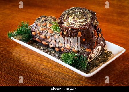 Gros plan de gâteau décoratif en rondins avec garnitures d'aiguille en pin sur une table en bois; Studio Banque D'Images