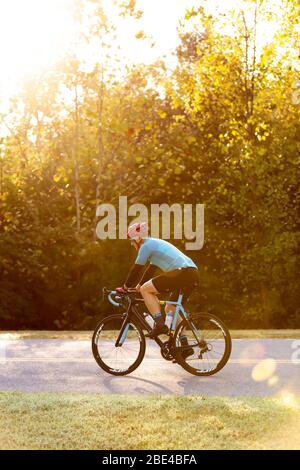 Cycliste sur une route aux rayons lumineux du soleil qui filtre les arbres, près du pont Trace Nachez; Franklin, Tennessee, États-Unis d'Amérique Banque D'Images