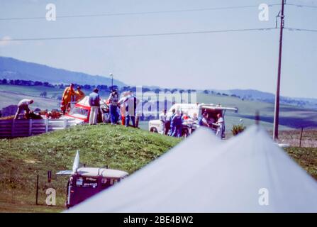 Bathurst, Australie, le 5 octobre 1986 : les membres de l'équipage d'ambulance et les marécages de sécurité des voies déplacent le conducteur blessé de course, Mike Burgmann à une ambulance d'attente après son impact de 260 km par heure avec des barrières de pneu près du fond du droit de la bielle de 2 km de long. Plus tard, Mike Burgmann est devenu le premier conducteur à mourir en compétition dans le Bathurst 1000 lorsqu'il a été déclaré mort à l'arrivée à l'hôpital de Bathurst voisin. L'année suivante, une chicane a été ajoutée à la bielle droite pour ralentir les pilotes et amener les 2 km droit à la norme mondiale de course. Banque D'Images