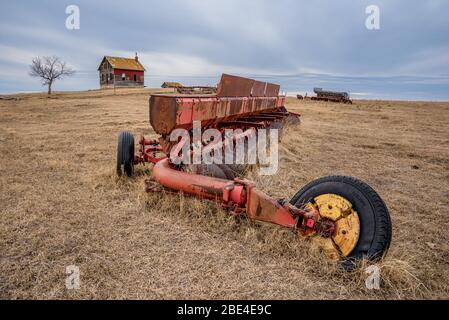 Coderre, SK- 9 avril 2020: Le disque Massey-Ferguson d'époque a été abandonné dans un pâturage avec une ferme à l'eau sur une colline en Saskatchewan Banque D'Images