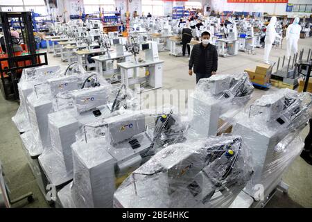 Qingdao, Chine. 11 avril 2020. Han Chuqi, chef de Nawon Machinery Co., Ltd., examine l'équipement d'étanchéité pour joints pour les vêtements de protection qui seront transportés en Corée du Sud à l'atelier de la société dans le district de Jimo de Qingdao, dans la province de Shandong en Chine orientale, le 11 avril 2020. Depuis sa reprise de la production le 7 février, Nawon Machinery Co., Ltd., investi par la Corée du Sud crédit: Xinhua/Alay Live News Banque D'Images