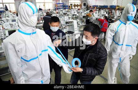 Qingdao, Chine. 11 avril 2020. Han Chuqi (R), chef de Nawon Machinery Co., Ltd., examine la qualité des bandes pour les vêtements de protection à l'atelier de la société dans le district de Jimo de Qingdao, dans la province de Shandong en Chine orientale, 11 avril 2020. Depuis sa reprise de la production le 7 février, Nawon Machinery Co., Ltd., investi en Corée du Sud, produit à pleine vitesse l'équipement d'étanchéité de joints pour les vêtements de protection, un équipement nécessaire mais non fabriqué en masse qui a été en court approvisionnement en raison de la propagation mondiale de la pandémie COVID-19. Crédit: Xinhua/Alay Live News Banque D'Images