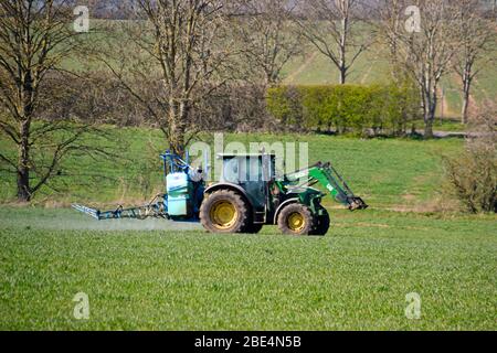 Tracteur pulvérisant des récoltes dans un champ à Haddenham, Buckinghamshire, Royaume-Uni Banque D'Images