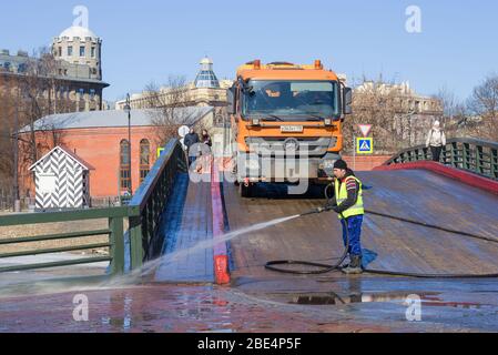 ST. PETERSBURG, RUSSIE - 07 AVRIL 2018 : un ouvrier lave un vieux pont en bois de la forteresse Pierre et Paul lors d'une journée de printemps ensoleillée Banque D'Images