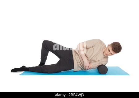 Un homme de handsome montre des exercices utilisant un rouleau en mousse pour un massage de libération myofasciale des points de déclenchement. Massage du muscle de l'épaule. Isolé sur blanc Banque D'Images