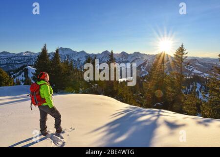 Femme profitant du coucher du soleil dans les montagnes enneigées. Alpes d'Allgäu, Tyrol, Autriche Banque D'Images