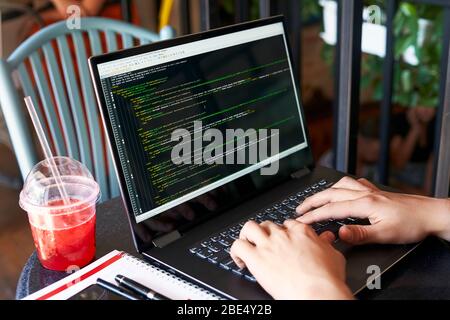 Programmeur développeur avec ordinateur portable. Le code du programme et de script à l'écran des données. Jeune travailleur indépendant dans les verres de travailler sur projet dans un café. Vue sur l'arrière Banque D'Images