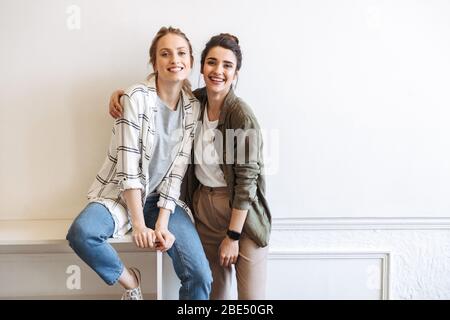 Happy girls standing au mur blanc à l'intérieur Banque D'Images