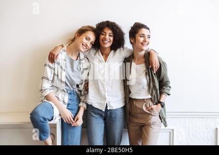 Happy girls standing au mur blanc à l'intérieur Banque D'Images