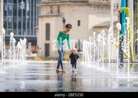 Birmingham, Royaume-Uni. 12 avril 2020. Mia, 12 ans, emmène son frère de 18 mois Jasper pour leur promenade d'exercice quotidien à travers les fontaines de la place du Centenaire, au centre-ville de Birmingham. Leur famille vit à proximité. Le dimanche de Pâques a commencé comme une journée chaude et ensoleillée. [Autorisation parentale accordée] crédit: Peter Lopeman/Alay Live News Banque D'Images