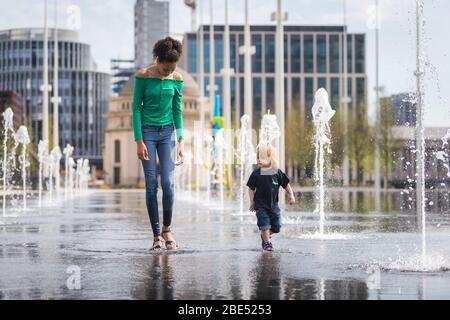 Birmingham, Royaume-Uni. 12 avril 2020. Mia, 12 ans, emmène son frère de 18 mois Jasper pour leur promenade d'exercice quotidien à travers les fontaines de la place du Centenaire, au centre-ville de Birmingham. Leur famille vit à proximité. Le dimanche de Pâques a commencé comme une journée chaude et ensoleillée. [Autorisation parentale accordée] crédit: Peter Lopeman/Alay Live News Banque D'Images