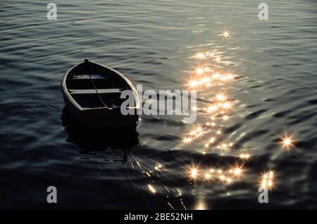 Petit bateau à ramer amarré avec eaux scintillantes en étoile dans le port de St Ives, Cornwall, Angleterre, Royaume-Uni. Banque D'Images