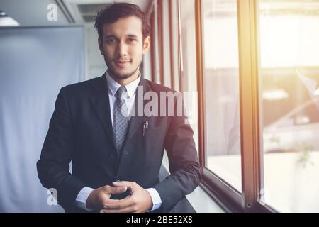 Happy handsome businessman standing and smiling in office Banque D'Images